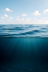 Obraz premium A serene view of the ocean with gentle waves under a partly cloudy sky, showcasing the beauty of the sea and the transition from surface to underwater