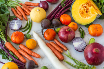 Freshly harvested seasonal vegetables and fruits arranged on a marble surface, creating a colorful and healthy food display