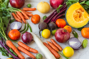 Freshly harvested seasonal vegetables and fruits arranged on a marble surface, creating a colorful and healthy food display