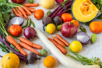 Freshly harvested seasonal vegetables and fruits arranged on a marble surface, creating a colorful and healthy food display