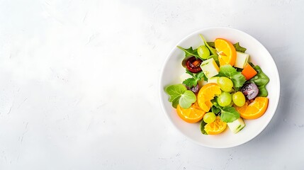 A vibrant fruit salad with oranges, grapes, and greens, isolated on white background