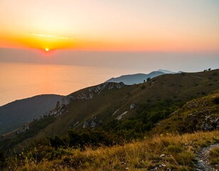 Obraz premium Sunrise over a mountain range overlooking a body of water