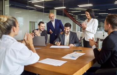 Business people sitting together at table with papers, making project, discussing sale statistics, analyzing financial report, posing at coworking space, making applauds after successful deal