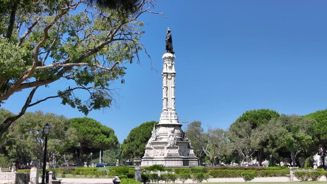 Monument to Afonso de Albuquerque in Lisbon Portugal framed by trees and bright blue sky