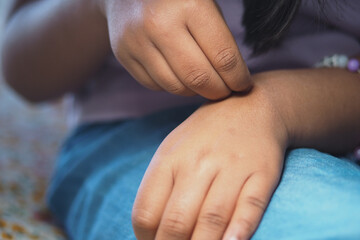 Child suffering itching skin while sitting indoors