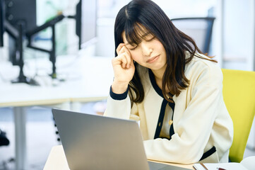 Obraz premium オフィスのデスクワークで疲れる女性