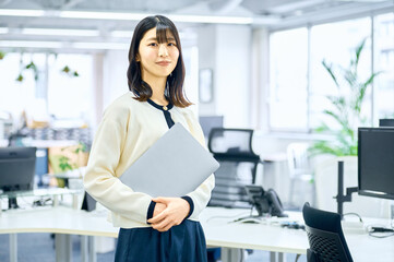 オフィスでノートパソコンを持つビジネスウーマン　ビジネスシーン