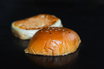 Toasted burger bun with sesame seeds on griddle surface, isolated food close-up.