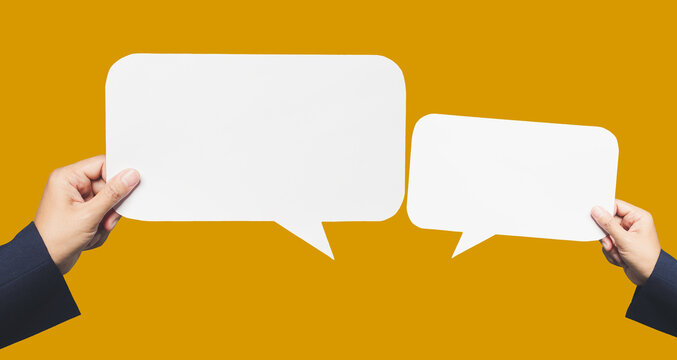 Hands holding blank white speech bubbles over yellow background for text or message.