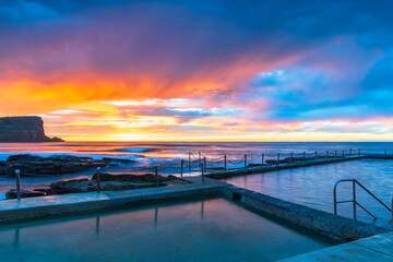 Obraz premium Winter sunrise by the sea pool with rain clouds