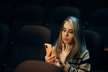 Woman in a Movie Theater Checking her Phone Waiting for her Date. Bored single lady doom scrolling during a play in a theater 