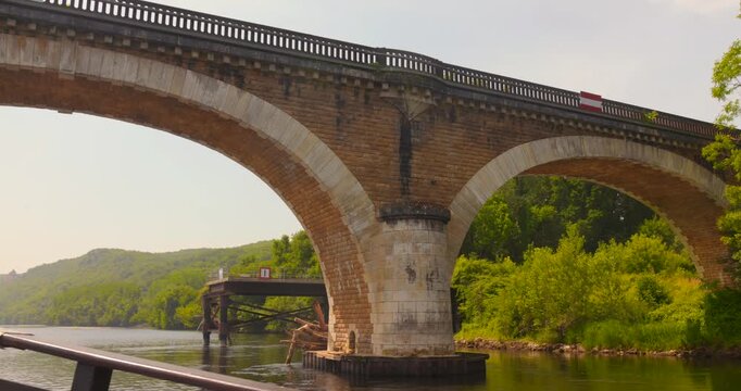 Shot of passing under stone bridge over Dordogne river, France. View from a traditional boat (gabare in French)