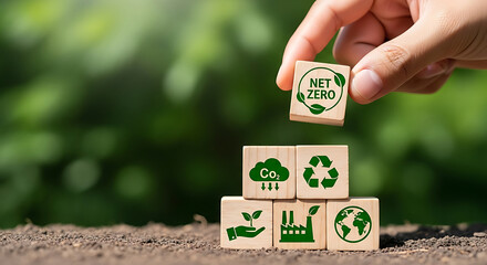 Net Zero carbon emissions concept. Hand stacking blocks with environmental symbols for a sustainable future.