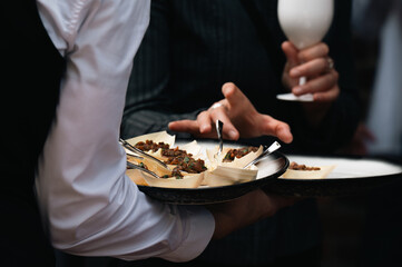 Elegant Server Presenting Gourmet Cuisine on a Tray at Upscale Event