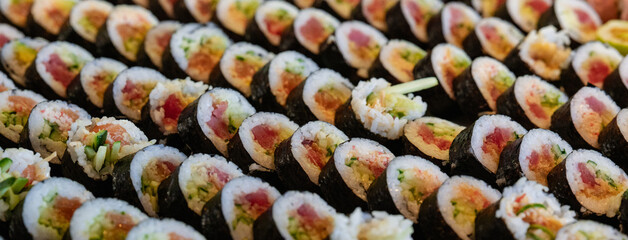 Neatly arranged rows of sushi rolls with colorful fillings and toppings