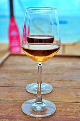 Red and white wine glasses stacked by the sea on a sunny day