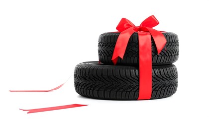 Two new tires, stacked, tied with a large red ribbon bow