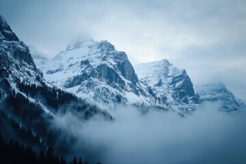 Fototapeta premium Misty Mountains Majesty: A Serene Winter Landscape of Snow-Capped Peaks and Mystical Fog