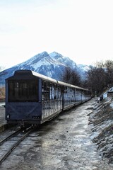 Scenic train on a track with a snowy mountain background in Ushuaia, Argentina, under a clear sky