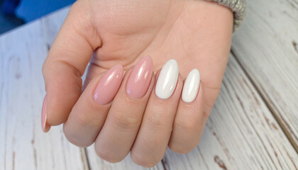 Elegant Manicure Displayed: A hand showcases a professional manicure featuring a collection of glossy, oval-shaped nails in diverse shades and styles, meticulously crafted for fashion-forward appeal.