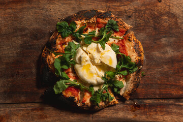 Bird's-eye view of a pizza with vegetables on top of a wooden board.