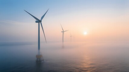Offshore wind turbines silhouetted against a misty sunrise over the sea