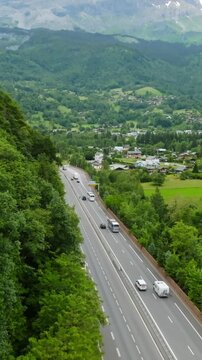 Vertical drone shot of traffic on road N205 and the Servoz village, in France