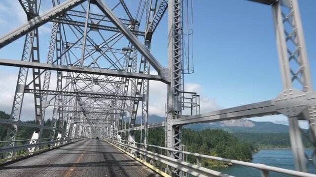 Steel truss spans the Columbia River at Cascade Locks, Oregon. Bridge of the Gods rises above forested hills and flowing water, blending engineering precision with Pacific Northwest grandeur.
