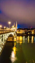 Naklejka premium Night cityscape with bridge and illuminated church reflected in calm water