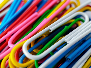 A collection of colorful paperclips scattered on a light surface. 