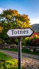 Rustic signpost in autumnal setting, points towards a quaint village path