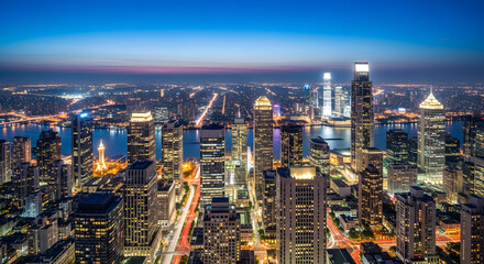 Naklejka premium Illuminated Metropolis Twilight: A vast cityscape unfolds under a captivating twilight sky, showcasing towering skyscrapers, glistening waterways, and arterial roads pulsing with vibrant life