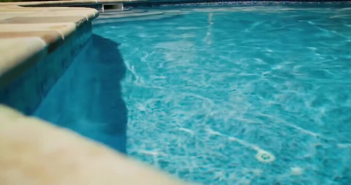 Close-up perspective of a swimming pool corner with shimmering turquoise water and stone coping, evoking summer serenity and refreshing leisure