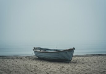 Naklejka premium Small fishing boat resting calmly on the beach sand in a misty sea coast scenery