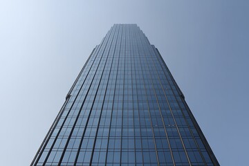 Fototapeta premium Looking up at a sleek, modern glass skyscraper reflecting the sky building architecture