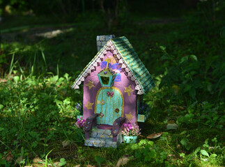 Cute fairy doll house on the grass outside in the garden. Lovely miniature for greeting cards, wedding or birthday concept, real estate, downsizing, home ownership. Vintage background