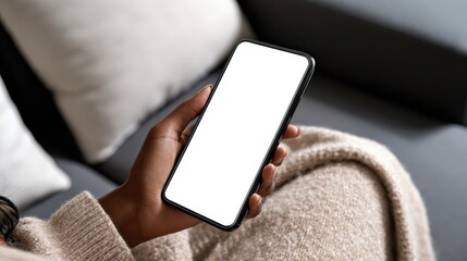 young black african woman holding smartphone in hand with white black empty mockup screen template using cell phone relaxing on sofa at home over shoulder view mobile apps advertising concept no logo