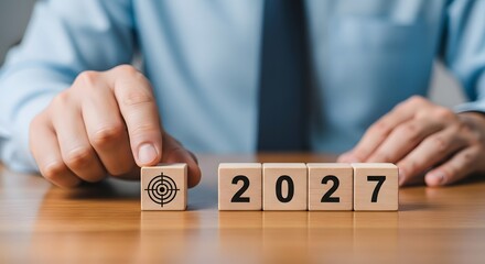 Person placing target block next to blocks spelling out year twenty twenty seven on table top view