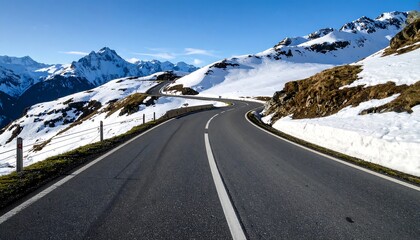 Winding mountain road, snow-covered peaks, sunny day