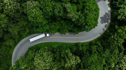 Aerial view semi truck trailer cargo on mountain curve road, Semi truck trailer cargo business logistic transportation on green forest road curve, Semi truck delivery asphalt road green forest tree.