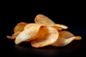 Golden crisp potato chips bask under dramatic lighting, embodying snack indulgence and National Potato Chip Day's salty celebration