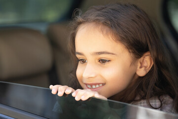 Headshot of a cute school-aged girl looking out of the car window