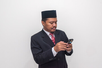Focused Indonesian Professional in Peci and Suit Browsing on His Smartphone