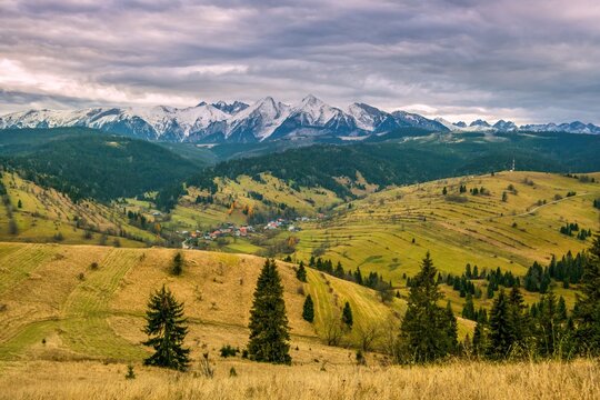 High Tatras autumn mountain valley. Autumn mountain village, with a beautiful autumn sun, snowy mountain peaks in the background. Mountain village in autumn landscape. Polskie gory