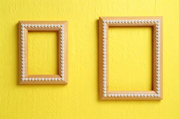 Fototapeta premium Two empty wooden frames with pearls on a yellow textured background