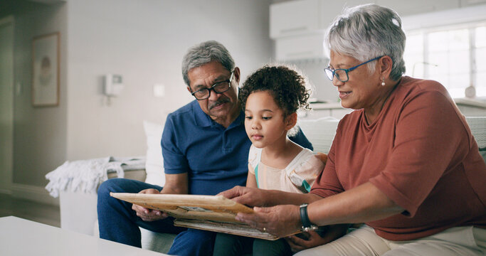 Grandparents, child and picture frame in home with family to share memory or learning history. Kid, grandmother and grandfather with photo on sofa for heritage, legacy and bonding with generations