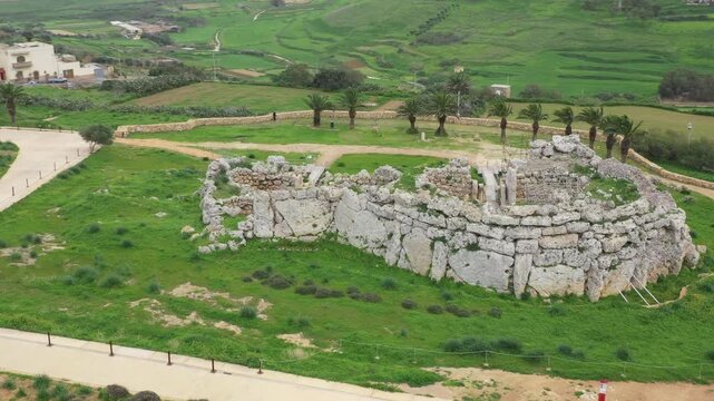 Drone shot of Ggantija Archaeological Park in Gozo with ancient stone temple ruins on green land