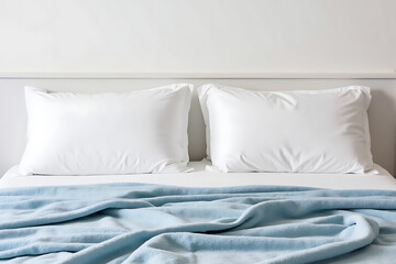 Serene Bedroom Scene with White Pillows and a Light Blue Blanket on a Bed Against a White Wall