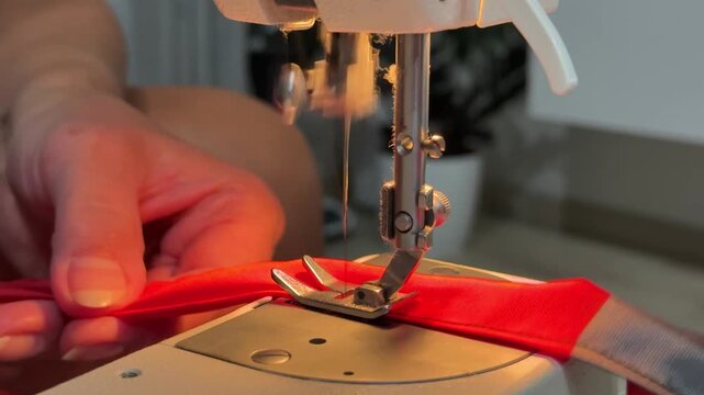 A woman sews clothes on a sewing machine, close-up of a moving needle and thread,