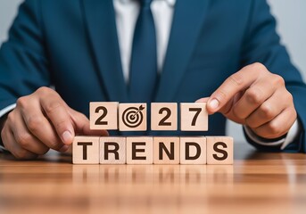 Man in suit arranging wooden blocks spelling trends and the year with target symbol for success